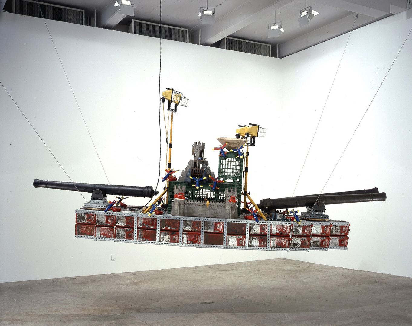 Chris Burden - Bateau de Guerre, 2001, 172 metal gasoline cans, 3 cannons on wooden swivels, 8 plastic torpedoes, 18 plastic submarine bombers, 4 plastic rescue submarines, 2 metal lamps, 5 plastic castle towers (2 on each side, 1 on top) with attached weaponry, 1 straw Chinese radar hat, 4 pl