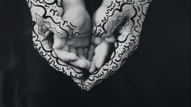 Shirin Neshat, Bonding, 1995. Photograph of a pair of children's hands resting on top of a pair of adult's hands (which have calligraphy drawn on them).