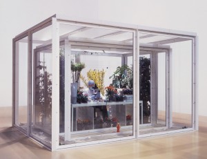 Damien Hirst - The Collector, 2003-2005, glass, painted steel, silicone rubber, aluminium, nylon netting, Formica, MDF, chair, animatronic man in laboratory wear, microscope, radiators, humidifiers, potted plants, flowers, live butterflies, butterfly specimens, cardboard and polystyrene specimen