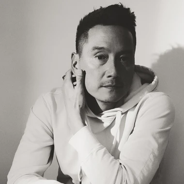 Black and white image of Glenn Kaino wearing a white hoodie