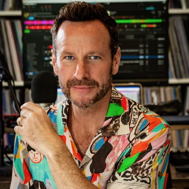 Jason Bentley seated in a recording studio surrounded by vinyl records and equipment