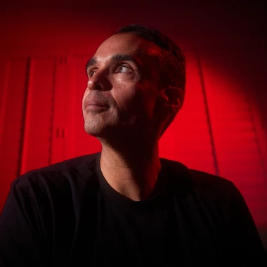 John Tejada seated under red stage lighting
