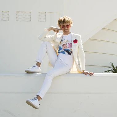 Luxxury seated outdoors in a white blazer