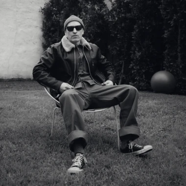 Peanut Butter Wolf sitting on a chair outside in black and white