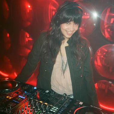 Bianca Lewis DJing in front of a red wall