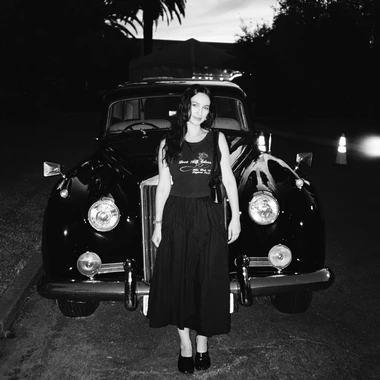 Black and white image of the artist in front of an old classic car