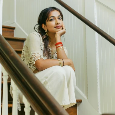 The artist Radha sitting on a interior staircase