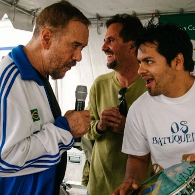 Three men playing music, one holding a microphone