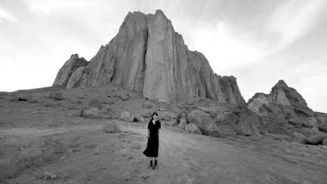 Video still of woman in front of a rocky landscape in New Mexico. Shirin Neshat, Land of Dreams video still, 2019.