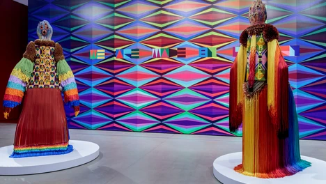 two multi-media human figure forms against a large multi-colored mural