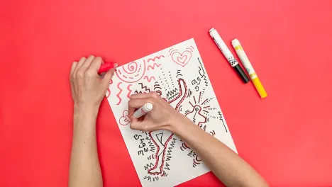 still of woman's hands drawing from the Keith Haring-inspired family art workshop