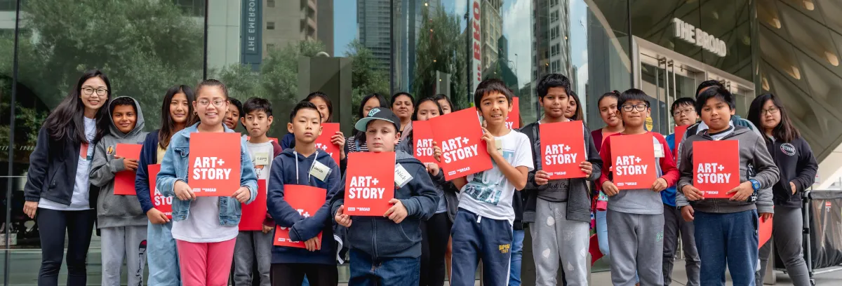 group of students with red Art+Story folders standing in front of the museum