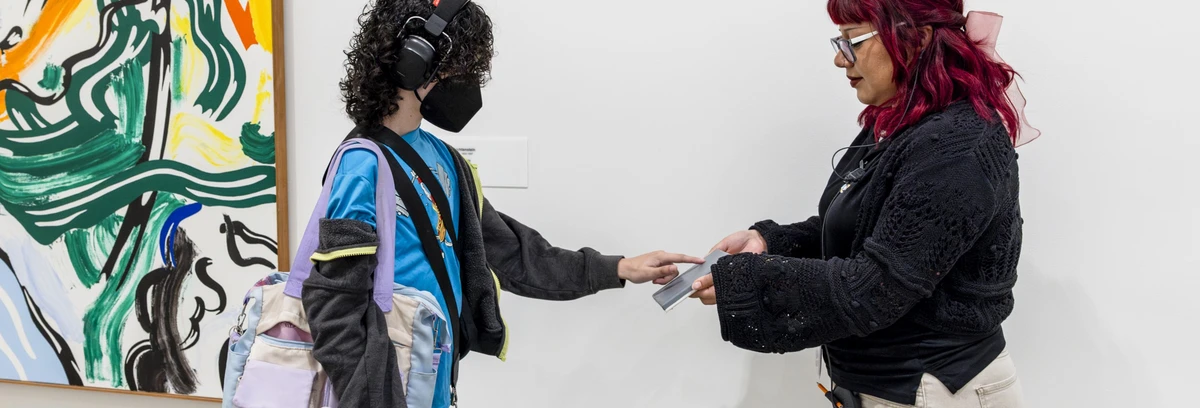 A visitor with headphones touching a sensory object at The Broad.