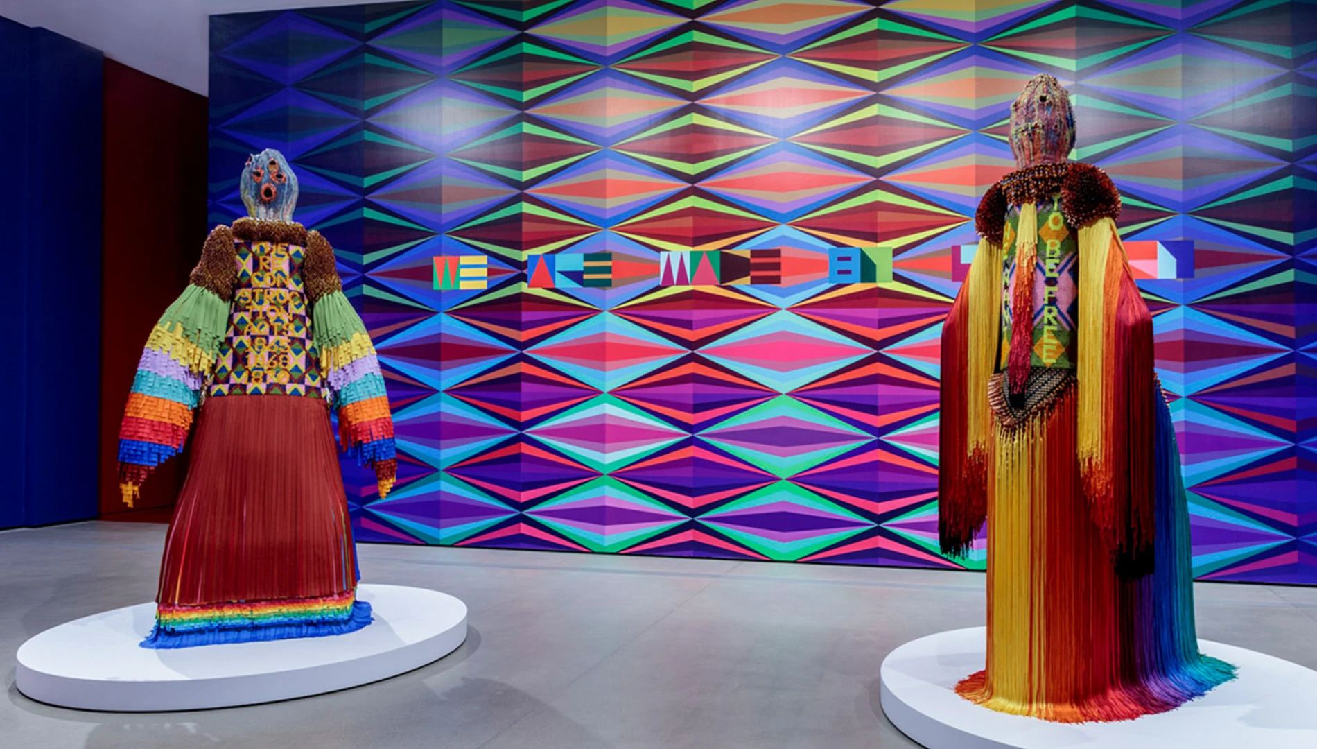 Large multi-media human figure forms against a multi-colored mural