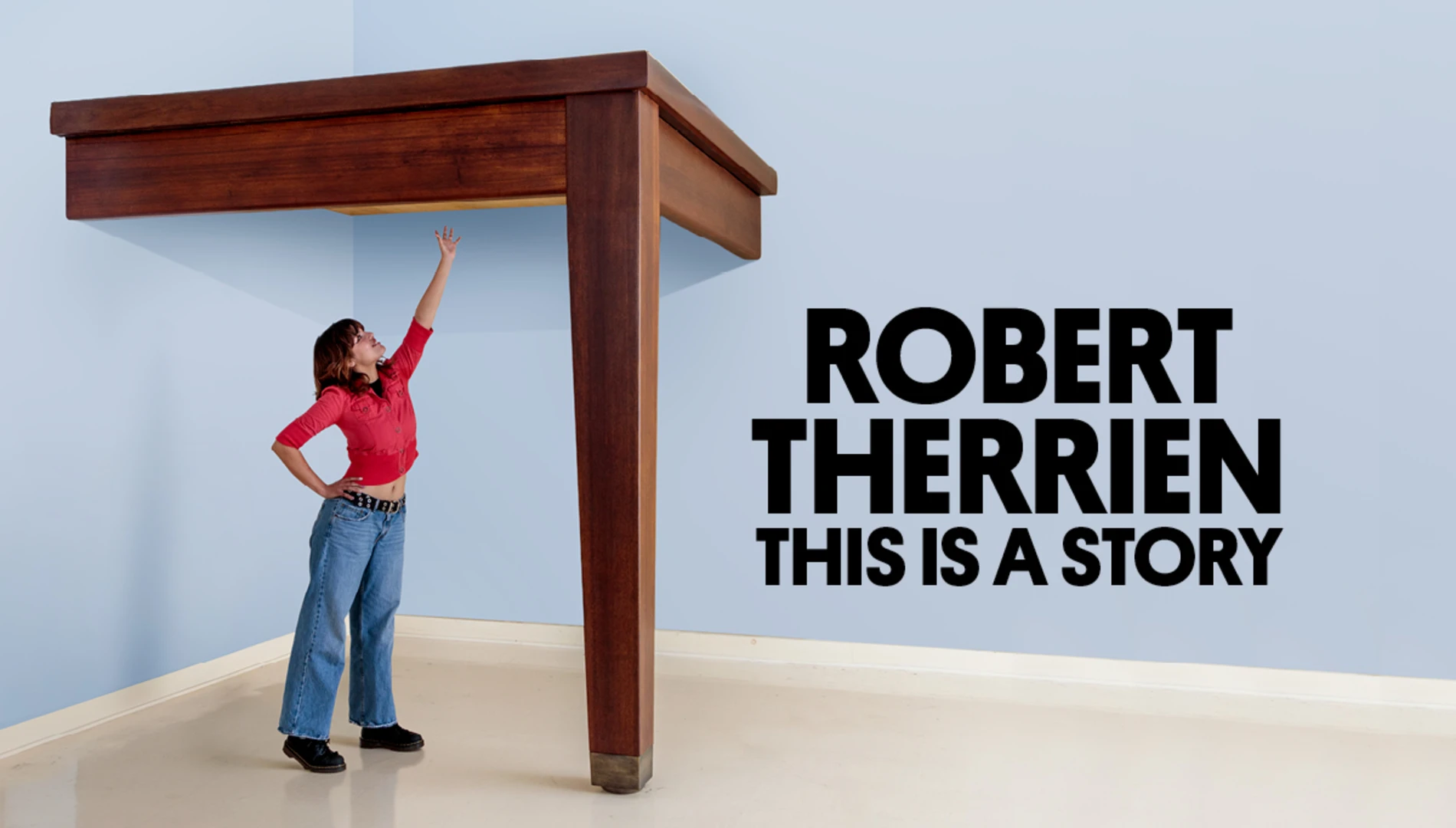A young woman reaching for a sculpture of an oversized dining table that she can't quite reach next to the exhibition title "Robert Therrien: This is a Story"