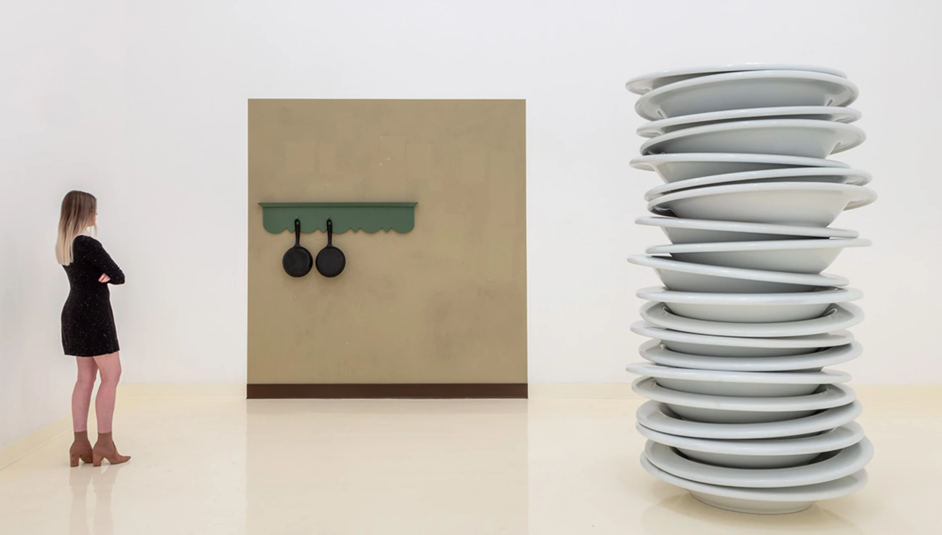 Woman in a black dress standing next to Robert Therrien's sculpture of an oversized stack of plates