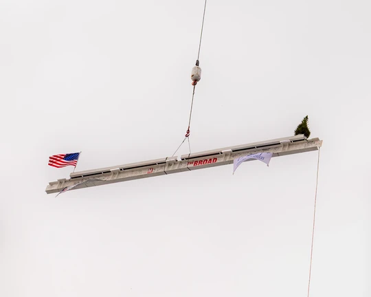 the final steel beam mid-air being lifted into place by crane