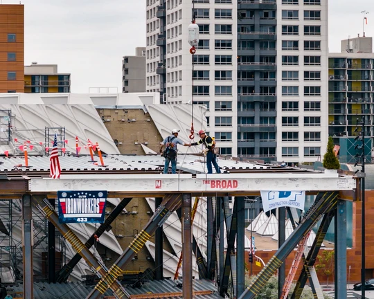 Two steelworks shaking hands atop the final beam after placing it on the expansion structure.