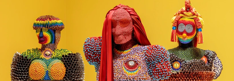 Exhibition photo of beaded figurines on yellow background