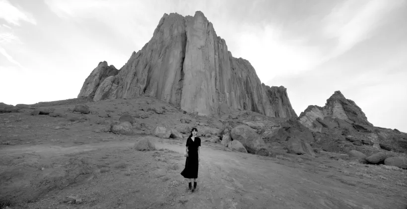 Video still of woman in front of a rocky landscape in New Mexico. Shirin Neshat, Land of Dreams video still, 2019.