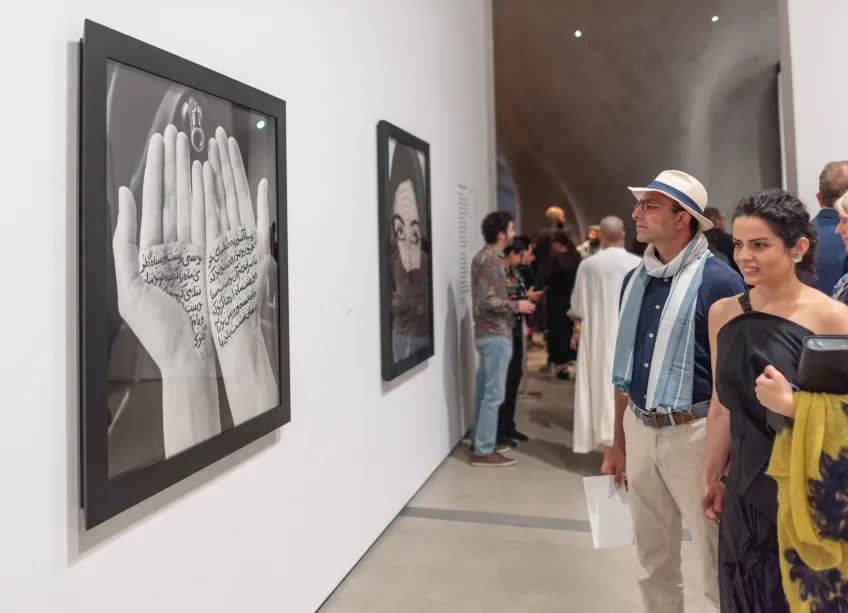 Photo of visitors looking at Shirin Neshat's work.