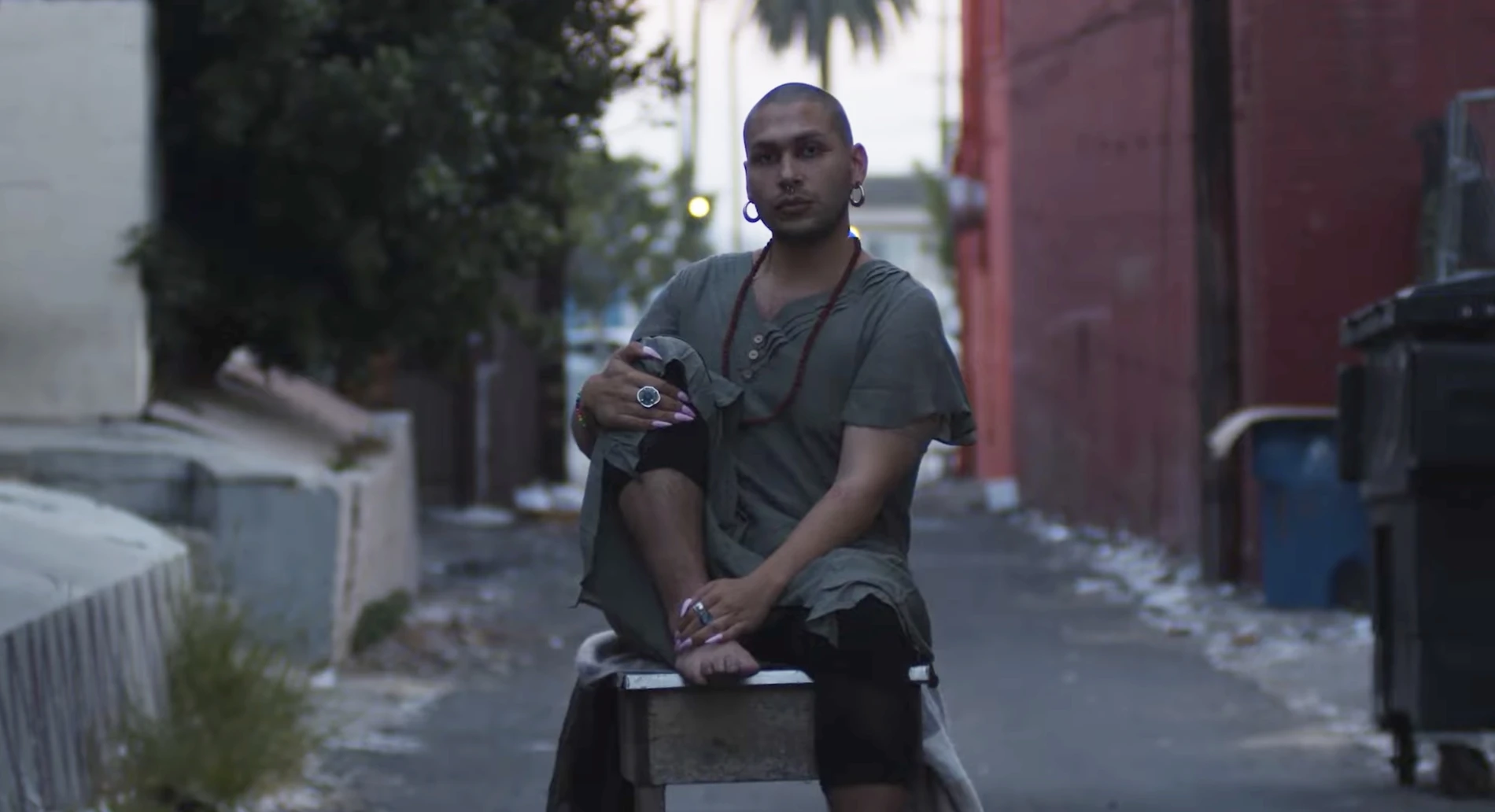 Man sitting on a stool in the middle of an alley.