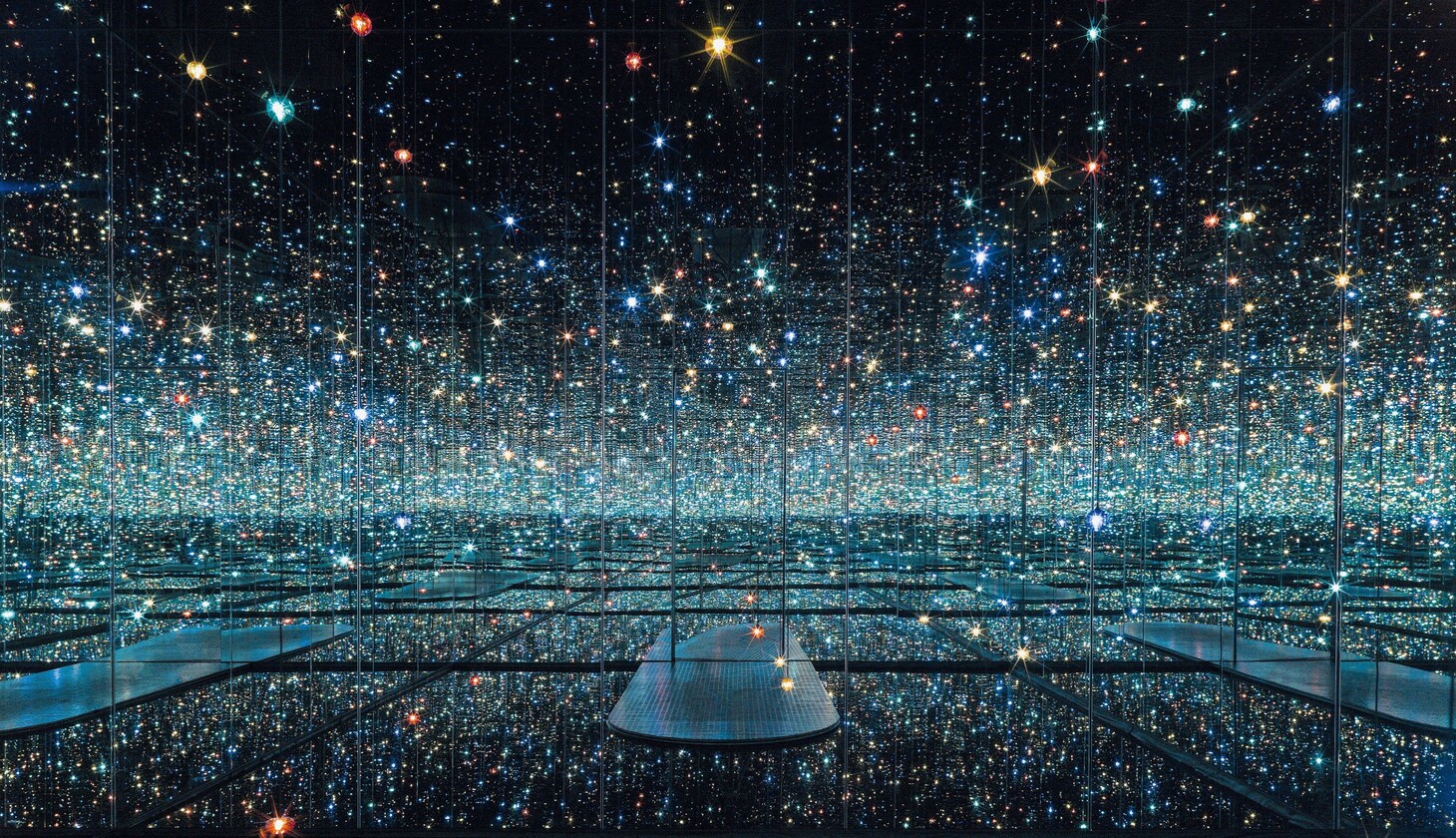 Infinity Mirrored Room at The Broad, a dark room with a blue hue with walls as mirrors and small lights dangling everywhere
