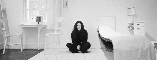 Black and White photo of Yoko Ono sitting cross legged in her Half Room artwork.