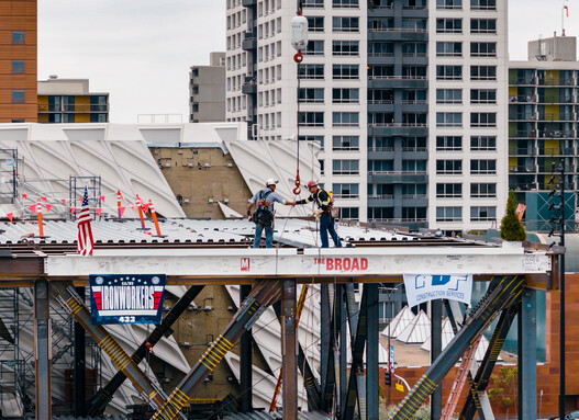 Two steelworks shaking hands atop the final beam after placing it on the expansion structure.