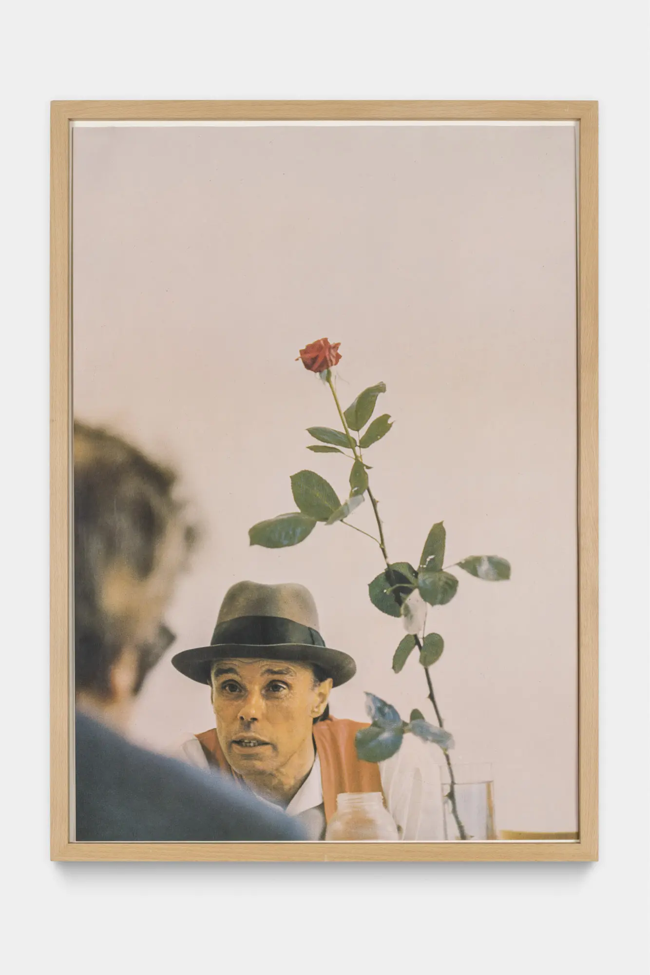 Photo of Joseph Beuys staring at a man who's back we see. There is a rose to their right.